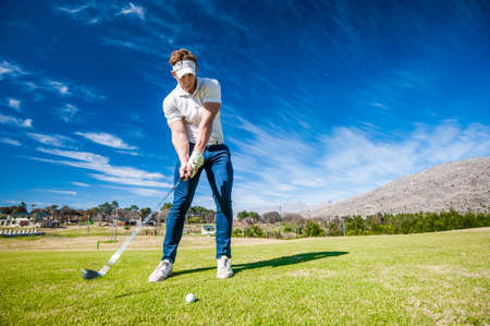 Close up image of a male golfer playing a shot on the fairway on a golf course in south africaの写真素材