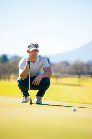 Close up view of a golfer planning his shot to the pin on a green on a bright sunny dayの写真素材