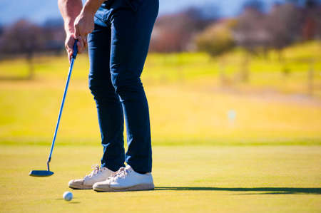 Close up view of a golfer planning his shot to the pin on a green on a bright sunny dayの写真素材