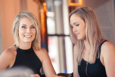 two blonde sisters in their twenties having a drink in a coffee shopの写真素材