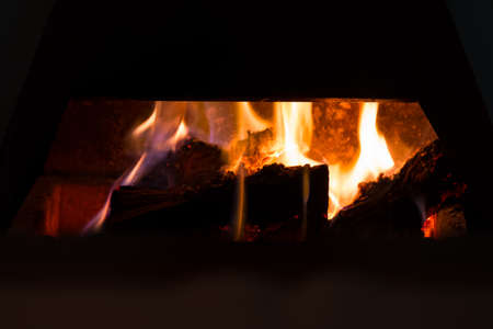 close up image of a log fireplace burning warmly with hot embersの写真素材