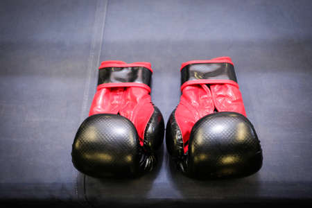 black and red boxing gloves laid on the edge of a boxing ringの写真素材