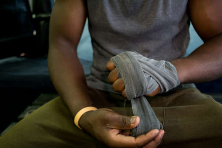black african boxer purposefully wrapps his fists with protective tape before putting on his boxing gloveの写真素材