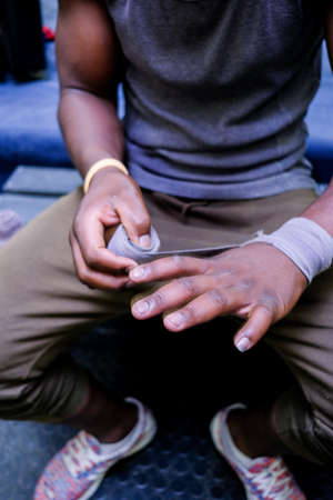 black african boxer purposefully wrapps his fists with protective tape before putting on his boxing gloveの写真素材