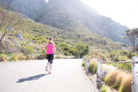 female running along a road with cape towns table mountain in the backgroundの写真素材
