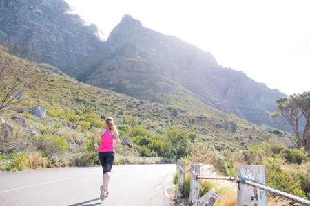 female running along a road with cape towns table mountain in the background