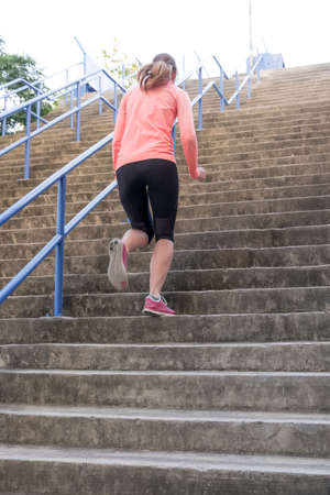 an athletic female sprinting up a flight of outdoor stairs as part of a high intesity interval...