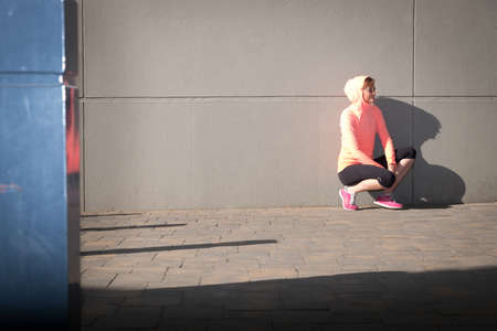 image of a female athlete stretching and recovering after a waork out in an urban setting
