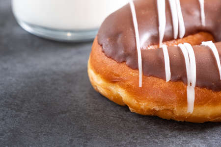 brown iced ring doughnut on a stone background with milk, a napkin and slate backgroundの写真素材