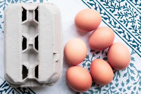 eggs and an egg box on a blue and white table cloth backgroundの写真素材