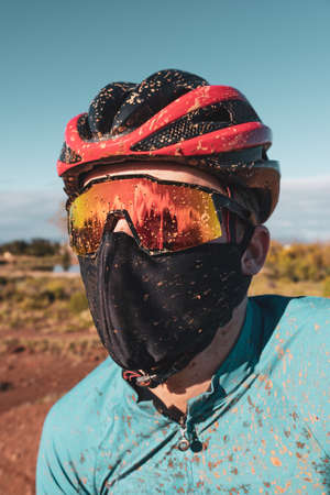 portrait of a dirty mountain biker wearing a face mask in the fight against COVID19 and corona virusの写真素材