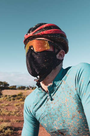 portrait of a dirty mountain biker wearing a face mask in the fight against COVID19 and corona virusの写真素材