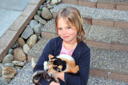 A girl and her cat sitting on stone stairsの写真素材
