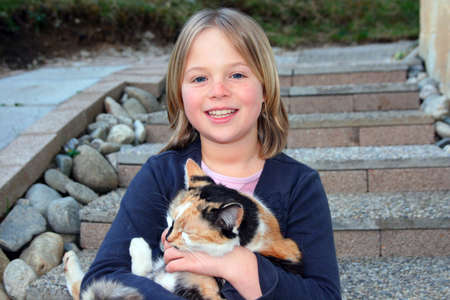 A girl and her cat sitting on stone stairsの写真素材