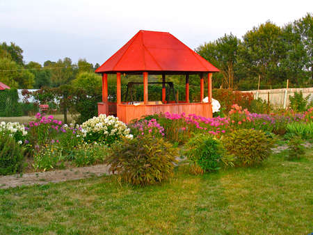 Wooden gazebo in floral garden at sunsetの写真素材
