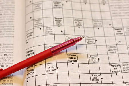 Crossword puzzle and pen. Shallow depth of field. Focus on metal end of penの写真素材