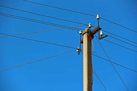 Power transmission lines against bright blue skyの写真素材