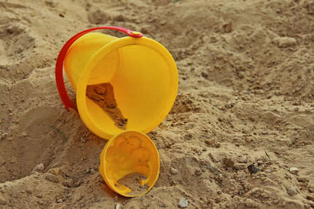 Yellow childrens bucket and mold, lying in sandbox. Shallow depth of fieldの写真素材