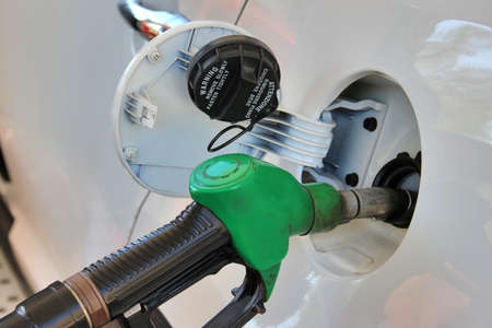 Opened tank and gun of gas station. Fuelling gasoline in car. Shallow depth of field