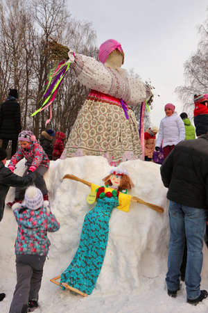 Children play in snow around scarecrow for festive holiday Maslenitsa, February 22, 2015, Tula, Russiaのeditorial素材
