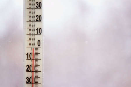 Outdoor thermometer with negative mark temperature on grey blurred background. Shallow depth of field. Focus on thermometerの写真素材