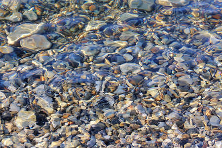 Colorful pebbles under blue sea shallow water