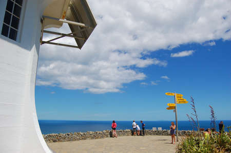 People at Cape Reinga lighthouse direction signs, Northland, New Zealandの写真素材
