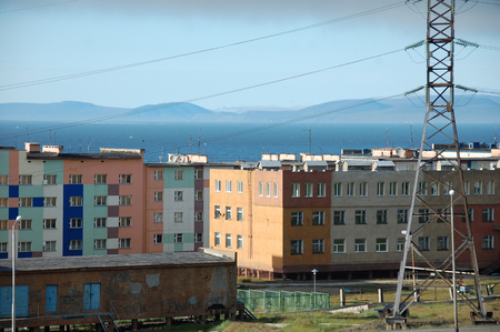 Apartment building block with hilly tundra coast in background, Pevek town, Chukotka, Russiaの写真素材