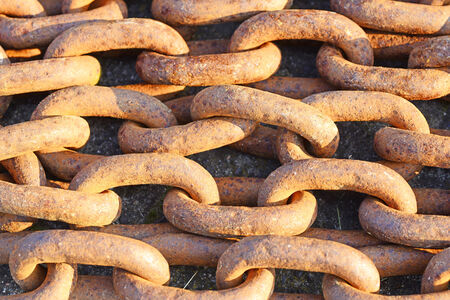 Closeup image of strong rusty chain in the morning sun