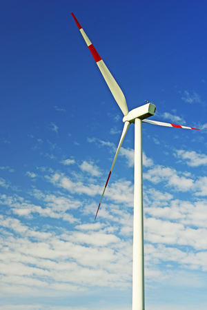 Image of a wind turbine with red stripes on the rotors against a blue skyの写真素材