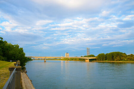 A landscape image of a river in the morning light with a cityscape in the distance