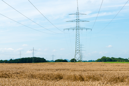 electricity pylons standing high in a field of crops in Germanyの写真素材