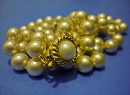 Vibrant yellow pearls necklace in blue backgroundの写真素材