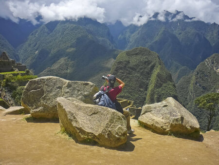 Young man taking photos on the highs in the famous Machu Picchu ancient city of the incas in Peru, South America のeditorial素材