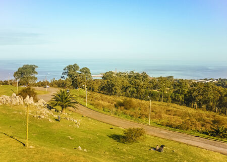 High angle view of Cerro de Montevideo park with a road a group of people sitting on the grass and the coast の写真素材