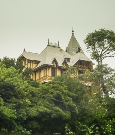 Low angle view medieval style house in yellow and pale green tones cover by big trees in the city of Mar del Plata, the most famous watering place in Argentina.の写真素材