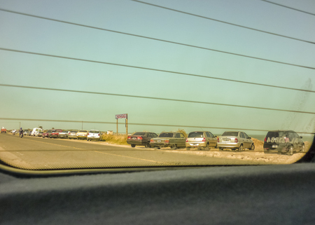 Car inside back sit road view with stationed cars and clean blue sky in the background.