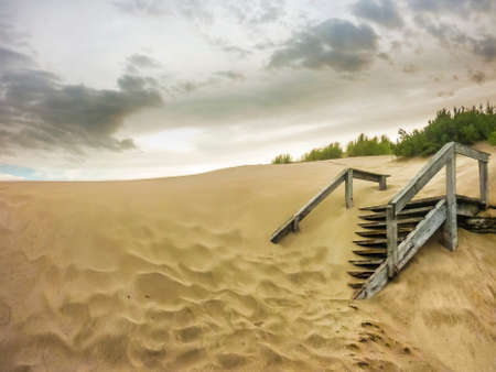 Wood staircase almost full cover by sand in the beach of Carilo, a luxury watering place in the outsides of Buenos Aires in Argentina.の写真素材