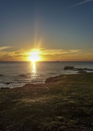 Beautiful sunset scene of the sea with silhouettes people at the breakwater in the city of Montevideo, Uruguay.の写真素材