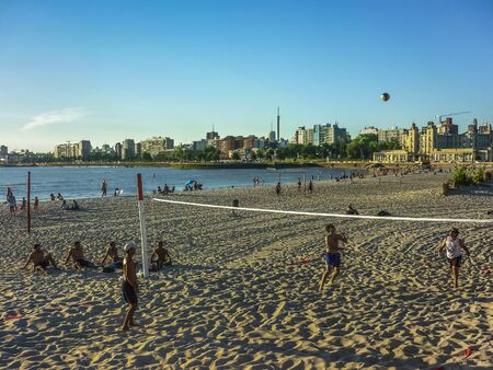MONTEVIDEO, URUGUAY, DECEMBER - 2014 - Group of men playing volley at the beach at summertime with skyline at Montevideo, the capital of Uruguay in South America.のeditorial素材