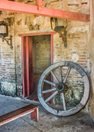 Door, antique lamps and wood wheel carriage in San Felipe de Barajas Fortress, an spanish colonial style defense building located in Cartagena,  Colombiaのeditorial素材