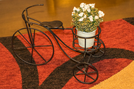 High angle view of cute handmade iron bicycle miniature with floral basket at the top of abstract pattern placementの写真素材