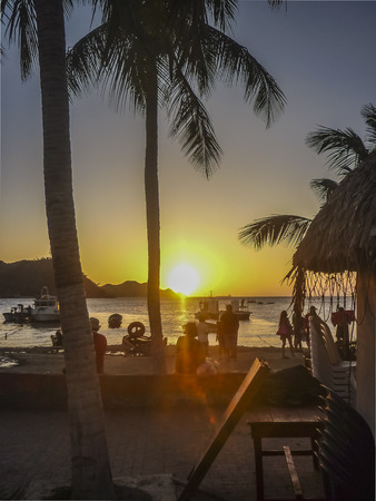 TAGANGA, COLOMBIA, JANUARY - 2015 - Beautiful sunset scene with boats and people silhouettes at caribbean bay called Taganga, one of the most important watering places in Colombiaのeditorial素材