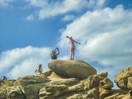 MAGDALENA, COLOMBIA, JANUARY - 2015 - Group of girls at the top of a rock with having fun up against sunny cloudy blue sky backgroundのeditorial素材