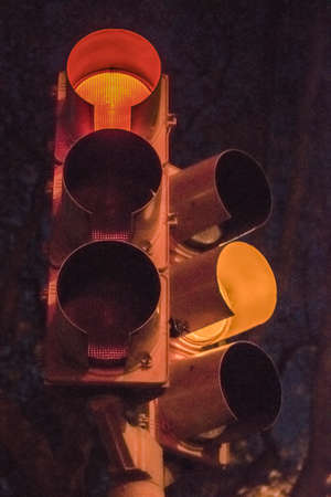 Vertical format low angle view night scene of traffic lights with yellow and red light turn onの写真素材