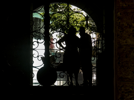 Mature couple and old style decorated door silhouettes with courtyard at the background in Cartagena de Indias, the most famous seaside resort of Colombia, South America.の写真素材