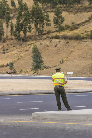 QUITO, ECUADOR, OCTOBER - 2015 - Back view of traffic policeman on the highway with mountain at background in the outsides of quito towards San Pablo lake in Ecuador, South Americaのeditorial素材