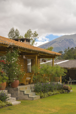 Touristic rustic style wood house with garden decoration and mountains and cloudy sky at background at San Pablo lake, Imbabura, Ecuadorのeditorial素材