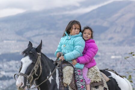 QUITO, ECUADOR, OCTOBER - 2015 - Two indigenous ecuadorian girls riding a horse at panecillo hill in Quito, Ecuadorのeditorial素材