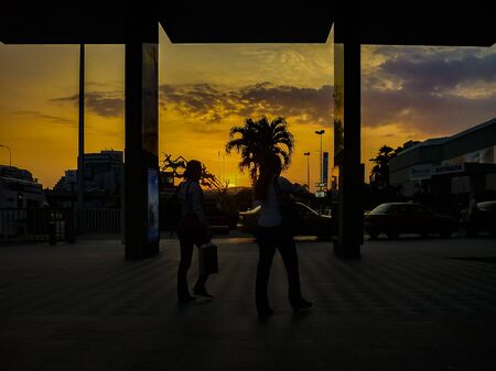 Sunset urban scene with silhouettes of palm trees and peopleのeditorial素材